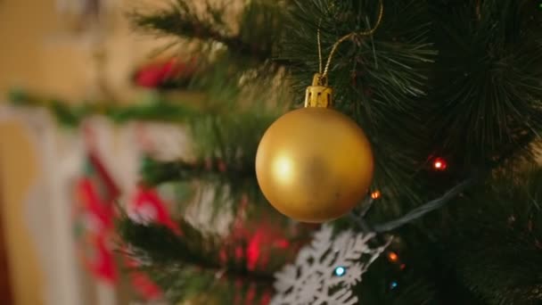 Steadicam-Aufnahme um die goldene Christbaumkugel, die am Weihnachtsbaum im Wohnzimmer hängt — Stockvideo