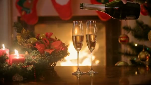 Closeup of hand pouring champagne in glasses on table at fireplace — Stock Video