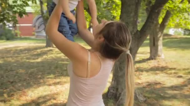 Steadicam záběr šťastná usmívající se žena zvedání a mazlení svého synka v parku — Stock video
