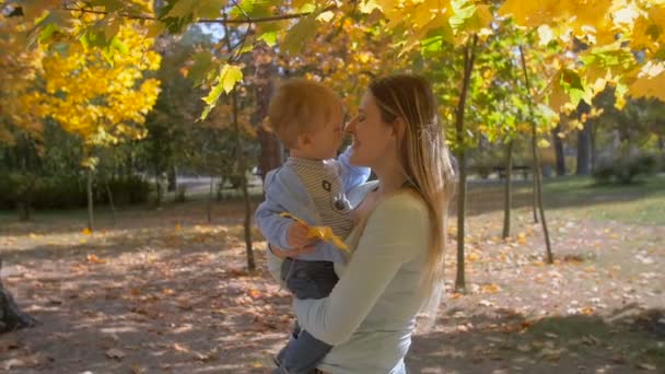Lassított felvétel, aranyos kisfiú játszik a fiatal anya őszi park — Stock videók