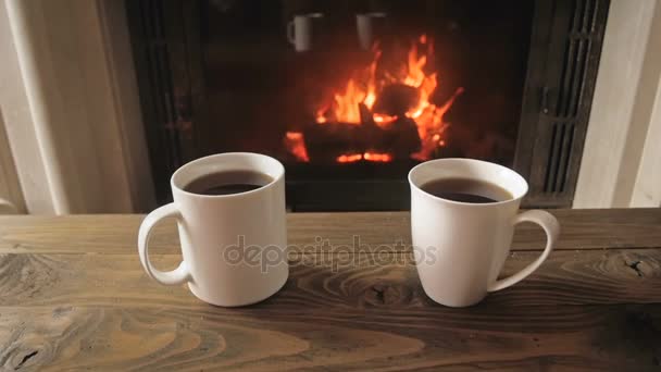 Vídeo en cámara lenta de dos tazas de té con chimenea en el fondo — Vídeo de stock