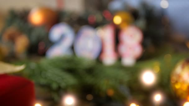 Filmagem 4k de câmera com foco em velas com números 2018 na árvore de Natal com luzes brilhantes e bugigangas coloridas — Vídeo de Stock