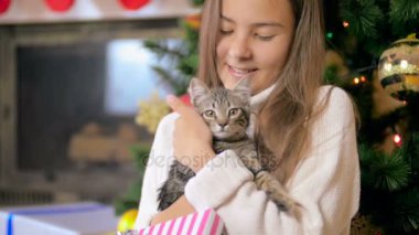 Holding ve yavru kedi Noel ağacının altında sevecen mutlu kız portresi