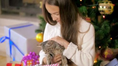 Sevimli kız Noel ağacının altında küçük kedi yavrusu sarılma ağır çekim görüntüleri