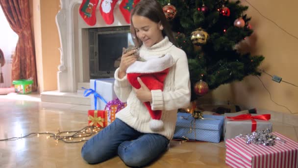 4k video of beautiful girl playing with litten under Christmas tree at living room — Stock Video