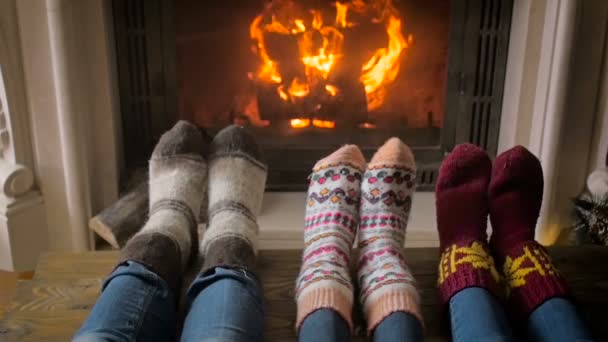 Vídeo en cámara lenta de pies en calcetines de lana de punto junto a la chimenea y el árbol de Navidad — Vídeos de Stock