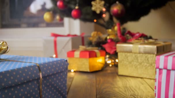 Красиві подарункові коробки на дерев'яній підлозі під ялинкою в будинку — стокове відео
