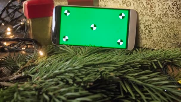 Closeup zoom in footage of mobile phone with Chroma Key green screen on decorated Christmas tree — Stock Video