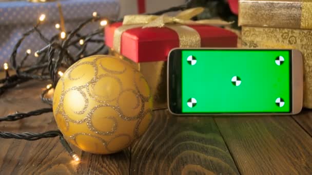 Closeup boneca tiro de telefone inteligente com tela verde cromakey entre decorações de Natal — Vídeo de Stock