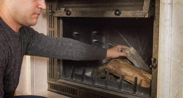 Nahaufnahme eines jungen Mannes, der Holz in den Kamin wirft — Stockfoto