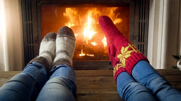 Feet wearing knitted wool socks warming by glowing fire at firep — Stock Photo, Image