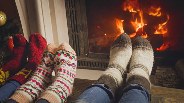 Closeup image of family with child in woolen socks warming by th