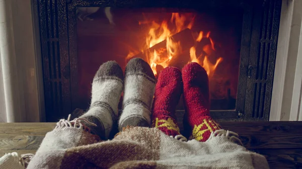 Closeup image of couple in knitted socks warming by the fireplac — Stock Photo, Image