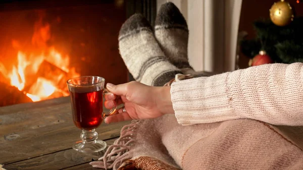 Toned closeup image of young woman holding cup of tea at burning — Stock Photo, Image