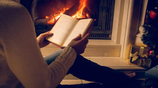 Toned foto da mulher lendo livro ao lado da lareira e queima — Fotografia de Stock