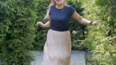 Parkta çalıların arasında çalışan ve kameraya gülümseyen mutlu genç kadın ağır çekim görüntüleri