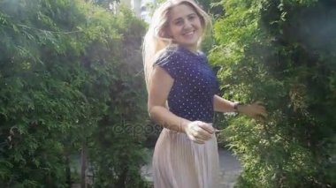 Pembe etek kamera uzak bahçesinde çalışan güzel bir genç gülümseyen kadın. Ağır çekim görüntüleri