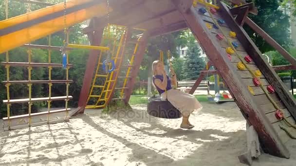 Медленное видео счастливой улыбающейся молодой женщины, веселящейся на детской площадке в парке — стоковое видео