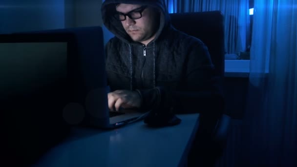 Filmagem 4k de hacker usando óculos e capuz trabalhando no laptop à noite — Vídeo de Stock