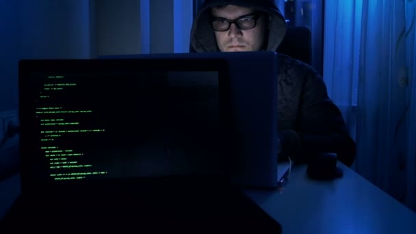 4 k beelden van hacker in brillen en kap werken bij nacht — Stockvideo