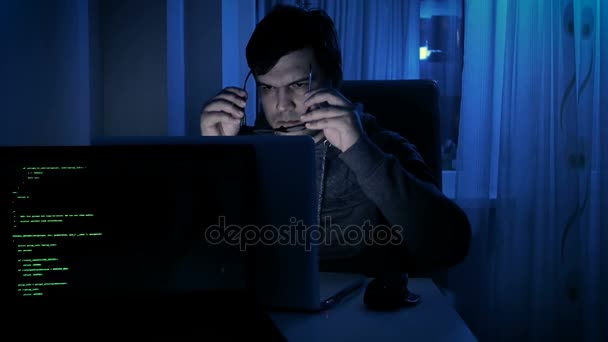 Filmati di un giovane uomo con cappuccio e occhiali che lavora al computer — Video Stock