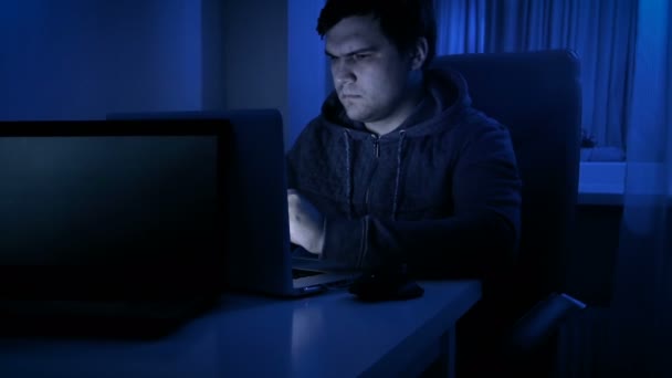 パーカーとコンピューターの使用の眼鏡を身に着けている若い男の映像 — ストック動画