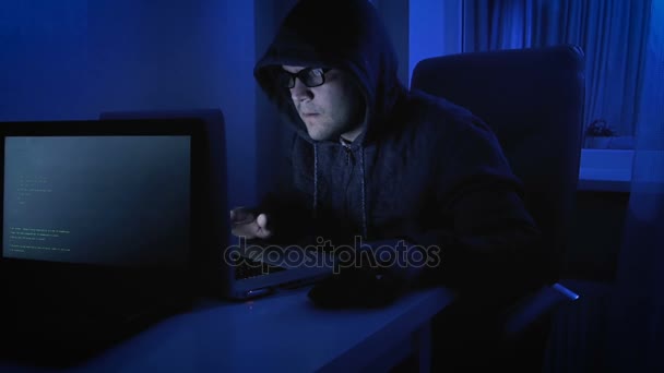 面白い 4 k 映像の男性のふりをするハッカー。夜のラップトップに取り組んでフードでこっけいな人間 — ストック動画