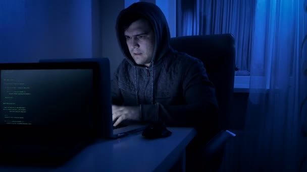 4k metraje del hombre estresado en la capucha trabajando en el ordenador portátil en casa por la noche — Vídeo de stock