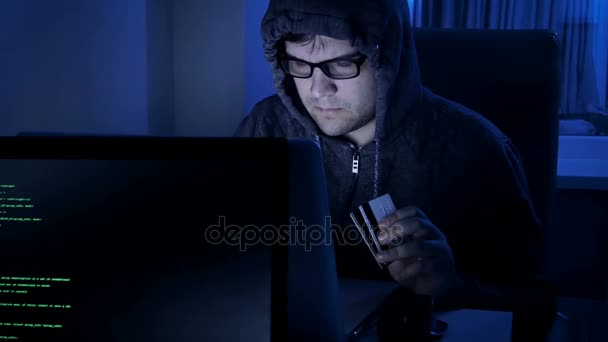 4k Filmmaterial von Hackern, die nachts arbeiten. Mann mit Kapuze stiehlt Geld von Kreditkarte — Stockvideo