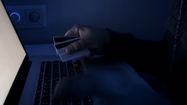 Съемка крупным планом человека, работающего на ноутбуке и держащего кредитные карты — стоковое видео