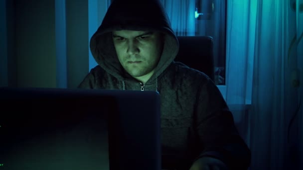 4 k film av unga manliga hacker i hoodie arbetar på laptop hemma i natt. Begreppet IT-relaterad brottslighet — Stockvideo