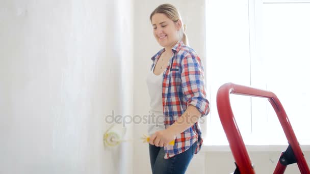 4 k 영상의 새로운 홈에 롤러와 아름 다운 웃는 여자 그림 벽 — 비디오