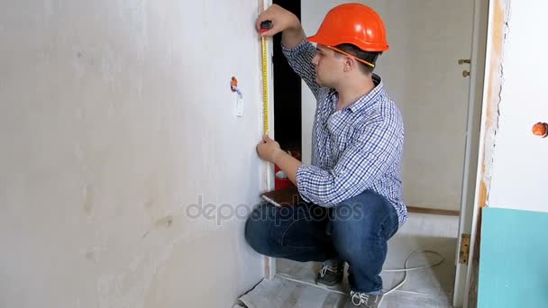 Πλάνα από νέους handyman σε hardhat μέτρηση τοίχων με ταινία μέτρησης — Αρχείο Βίντεο