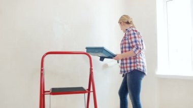 Ağır çekim görüntülerini yenileme yapma ve boyama duvarları yeni evinde güzel gülümseyen genç kadın