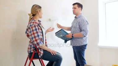 Genç çift boyama duvarları boya silindiri ile ağır çekim görüntüleri