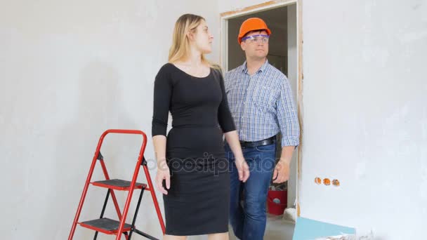 新しい家の彼の女性の上司の改修を示す男性の職長の 4 k 映像 — ストック動画