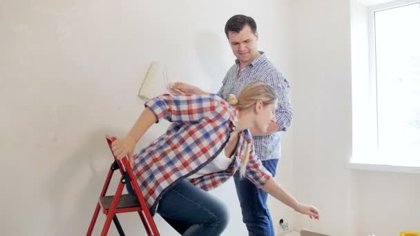 Footage of happy young couple having fun while painting walls at new home — Stok Video