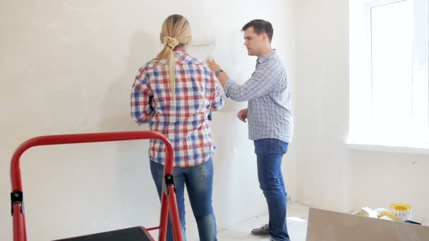 Filmagem em câmera lenta de um jovem com a esposa pintando paredes na nova casa — Vídeo de Stock