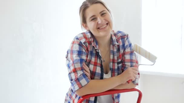 Slow motion-film av vacker ung kvinna poserar med paint roller i nya hus under renovering — Stockvideo
