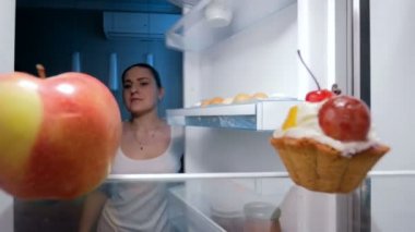genç kadın tatlı pasta buzdolabı mutfak alarak 4 k görüntüleri. Sağlıksız yiyecek ve diyet kavramı