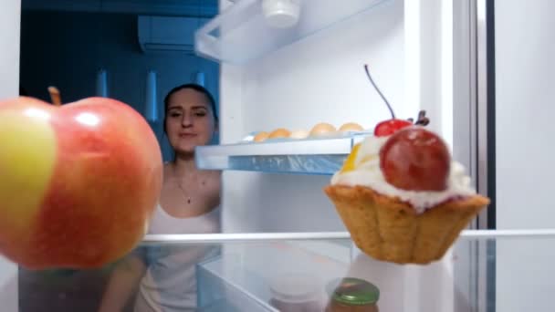 4k filmato di giovane donna che prende dolce torta dal frigorifero di notte — Video Stock