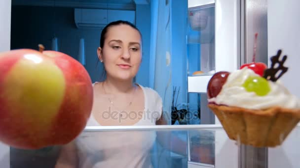 Imagens em 4K de uma jovem a tirar maçã fresca do frigorífico da cozinha. Conceito de alimentação e nutrição saudáveis — Vídeo de Stock