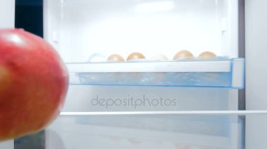 Aç genç kadın sneking buzdolabı ve ısırma apple 4 k görüntüleri. Sağlıksız beslenme kavramı