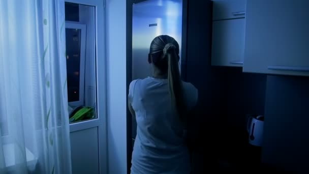 Slow motion footage of young woman takes apple from refrigerator at night — Stock Video