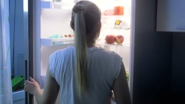 Slow motion video of young hungry woman looking for food at night — Stock Video