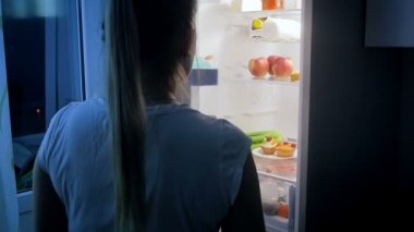 Genç kadın sağlıklı gıda seçimi. Kız buzdolabı açar ve pasta yerine sebze alır