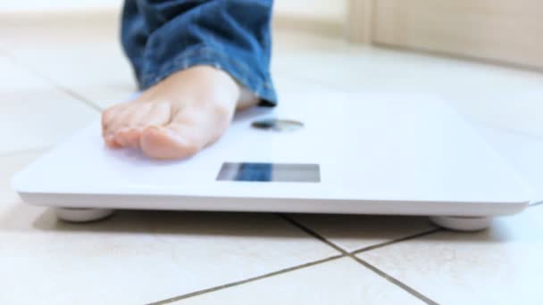 4k dolly video of young woman stepping on electronic weight scales — Stock Video