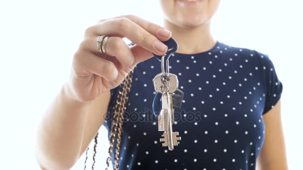 4k close seup video of young smiling woman holding home keys against white background — стоковое видео