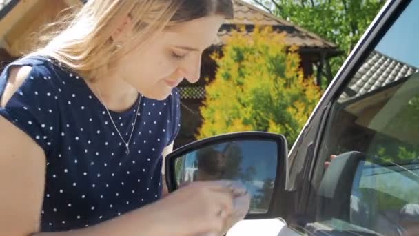 4 k close-up beelden van jonge vrouwelijke bestuurder auto side mirror met doek schoonmaken — Stockvideo