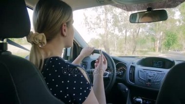 Genç kadın sürücü araba sürüş sırasında ruj uygulayarak ağır çekim görüntüleri